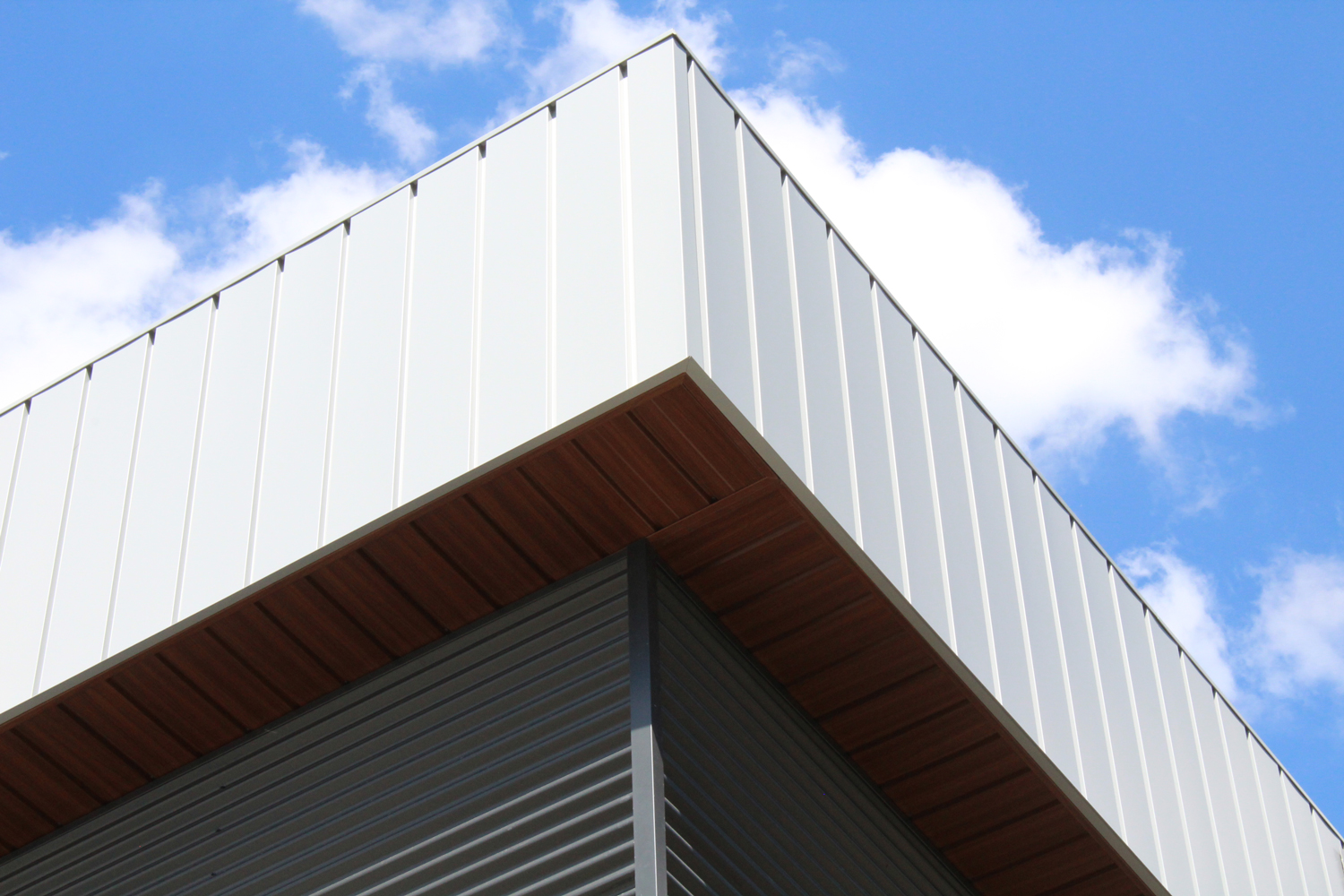 Commercial Building with 7/8 Corrugated in Carbon, Espresso Woodgrain Soffit, and custom panels in Melchers Green and Bright White