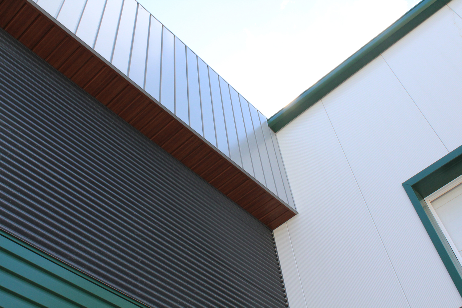 Commercial Building with 7/8 Corrugated in Carbon, Espresso Woodgrain Soffit, and custom panels in Melchers Green and Bright White