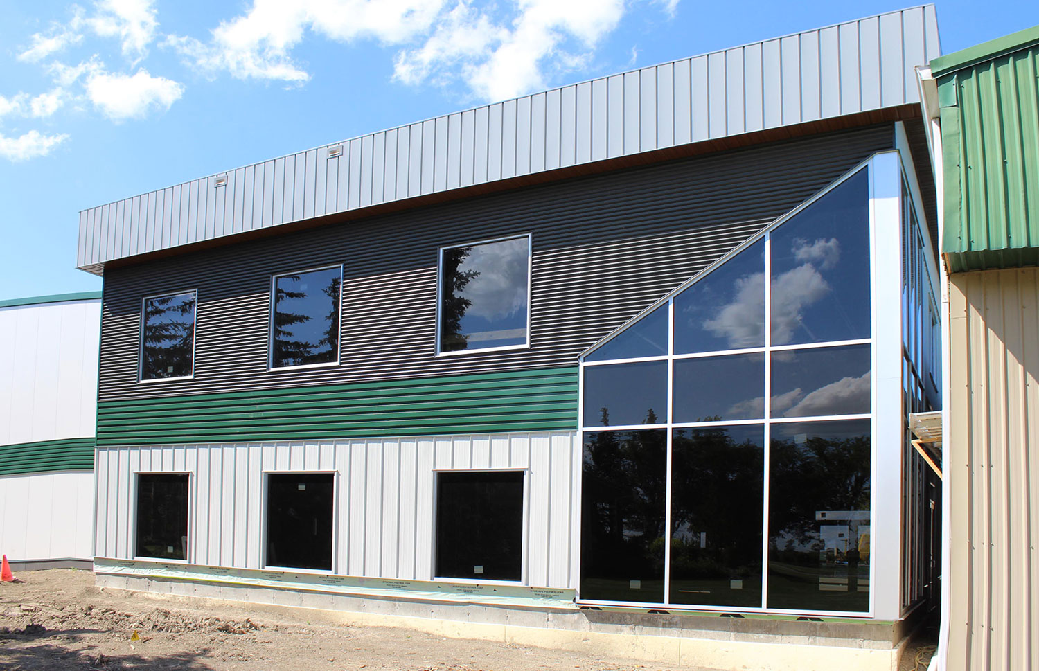 Commercial Building with 7/8 Corrugated in Carbon, Espresso Woodgrain Soffit, and custom panels in Melchers Green and Bright White