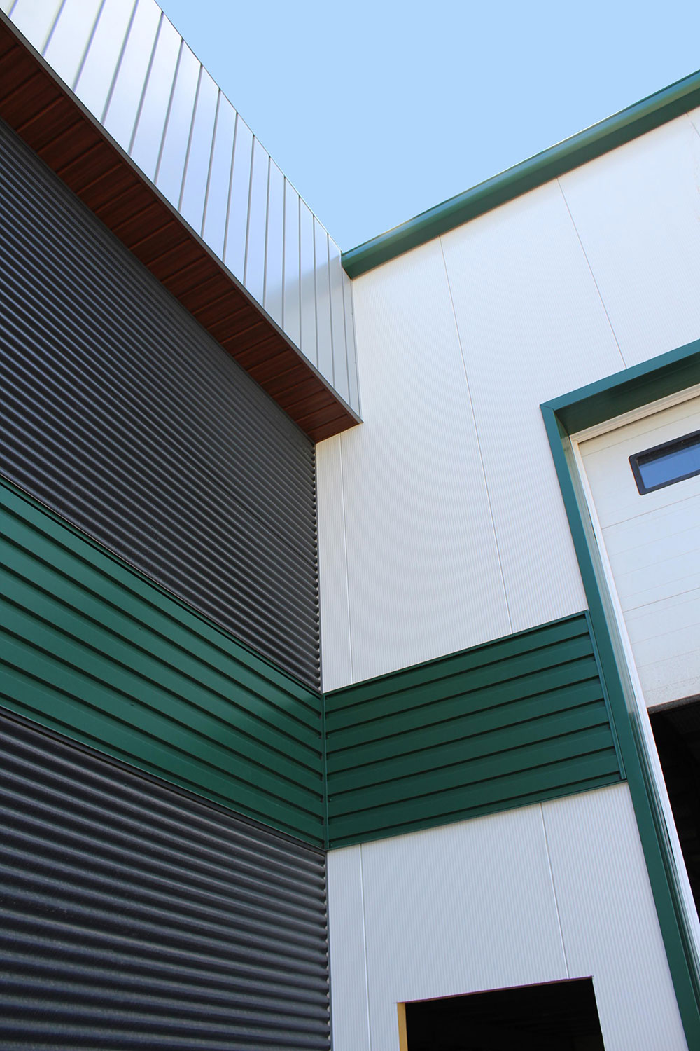 Commercial Building with 7/8 Corrugated in Carbon, Espresso Woodgrain Soffit, and custom panels in Melchers Green and Bright White